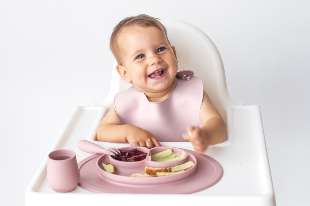 Baby zufüttern- Baby im Hochstuhl vor seinem Essen