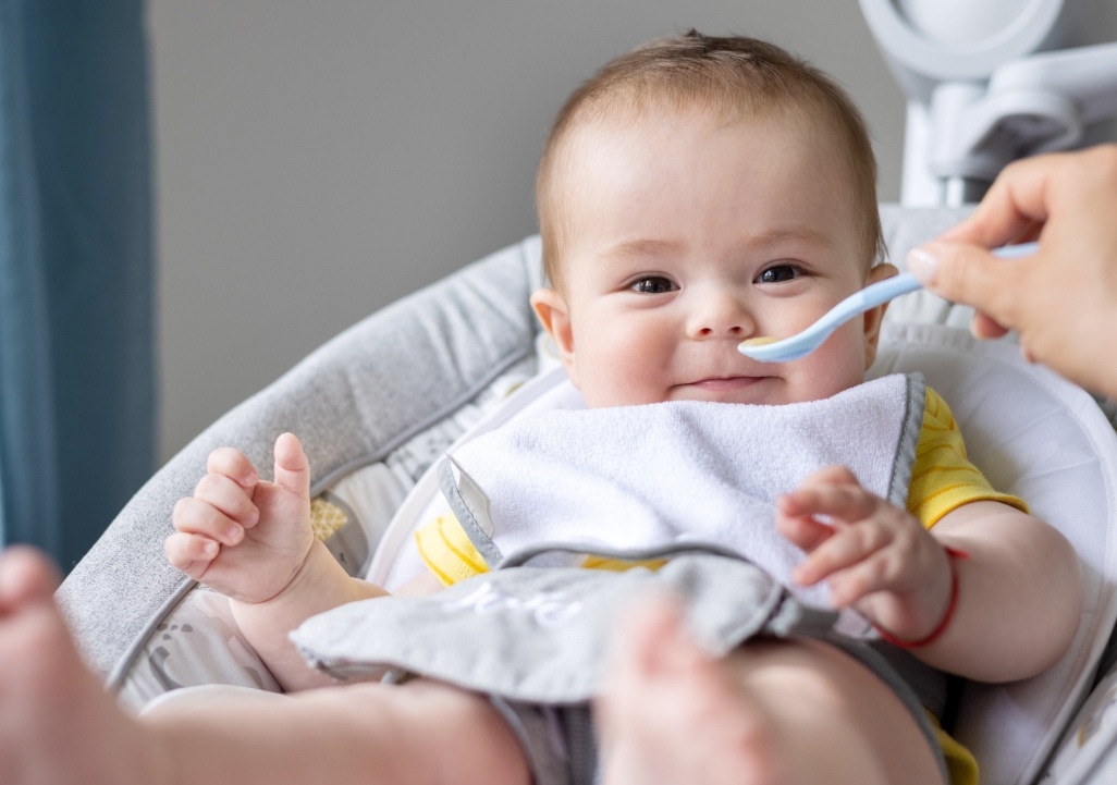 Baby zufüttern-Lachendes Baby in Babyschale