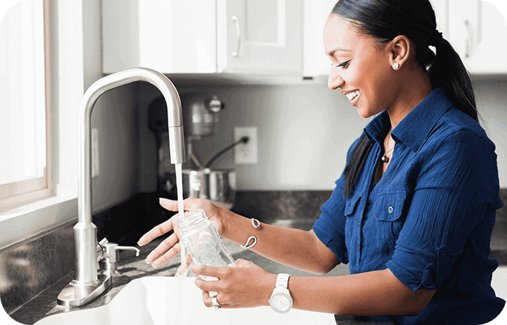 Mutter reinigt Babyflasche mit Wasser